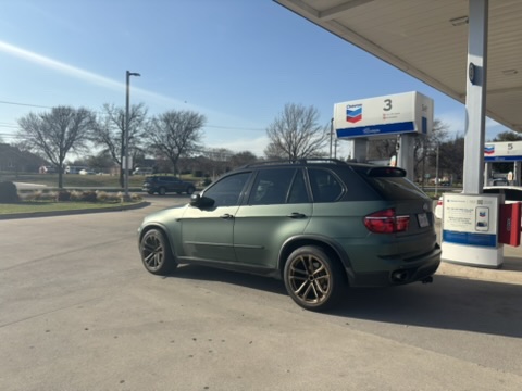 Matte green BMW X5 at a gas station