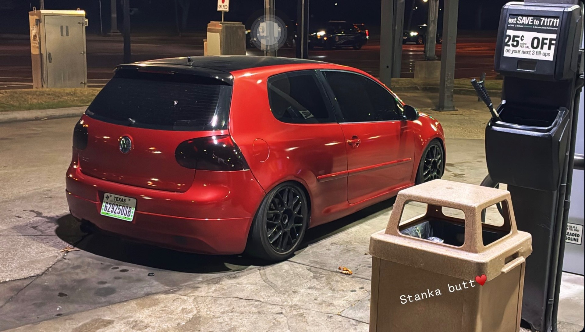 Red Volkswagen Golf GTI with black roof and black wheels at a gas station